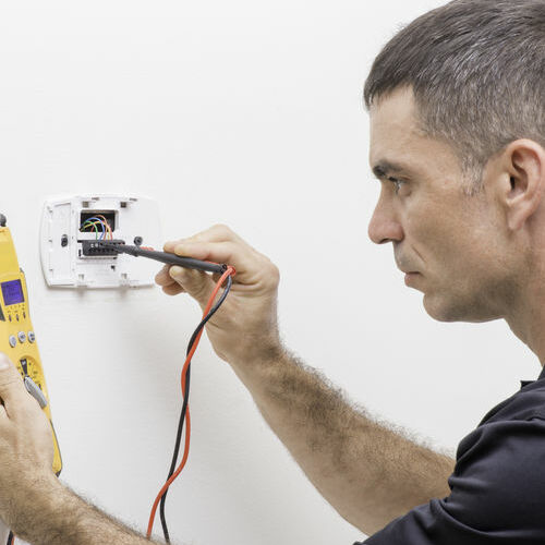 A Technician Checks a Thermostat.